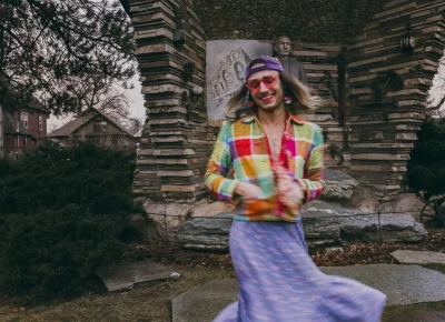 Bly Wallentine applyss lipstick while wearing a colorful outfit.