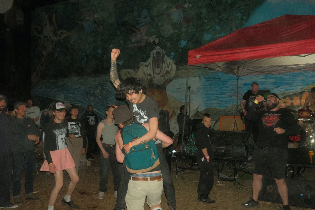 Someone gives a piggy back ride in an outdoor mosh pit.