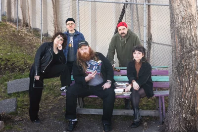 The band sitting on a bench reading a book.