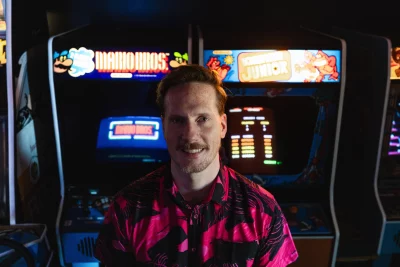 A man standing in front of some arcade cabinets.