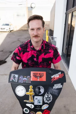 A man holding a television covered in stickers.