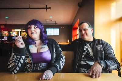 Two people sitting at a booth in an arcade.