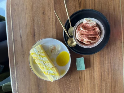 A slice of yellow cake and a cream-topped dessert on a table. 