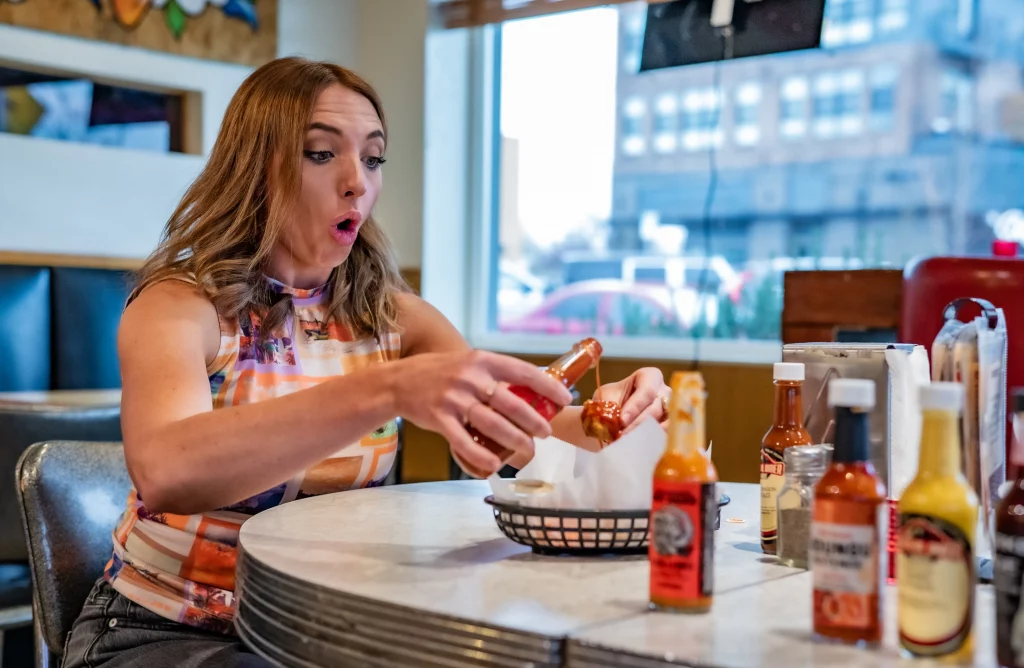 Cobair Collinsworth looks shocked as she pours out hot sauce.