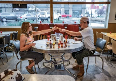 Bueche and Collinsworth cheers with vegan wings over a table. 