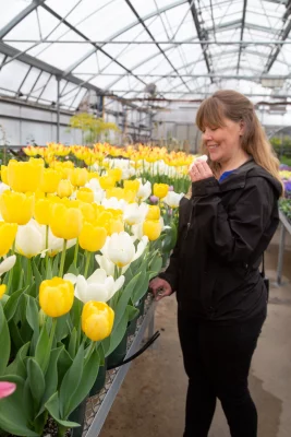 Woman standing next to a lot of tulips.