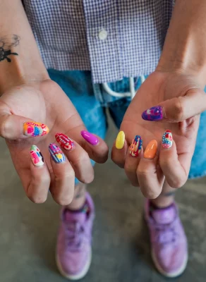 A guest of Wicked West Nails holds up their hands to show the colorful work they had done.