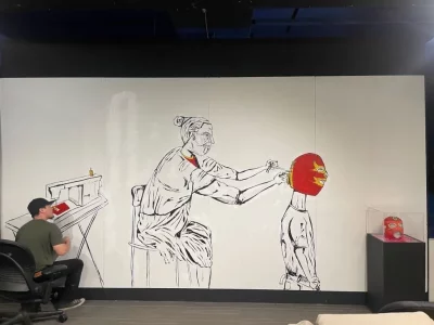 Mural artist Beto Conjeo works on a mural of a young luchador with a red mask being put on by the subject's elder.