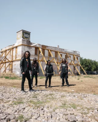 Four guys standing in front of an abandoned building.