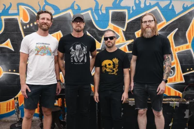Four guys standing in front of a graffiti wall.