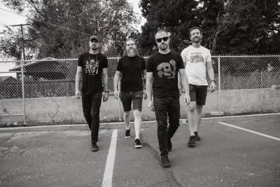Four guys walking in a parking lot.