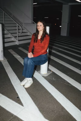 A woman leaning up against a pole.
