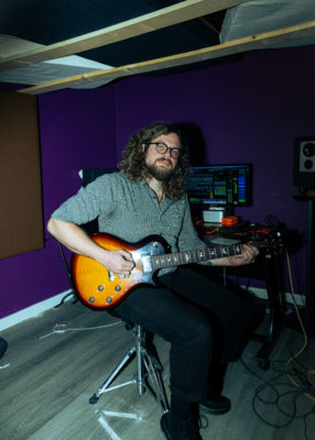 Cutler sitting with a guitar. 