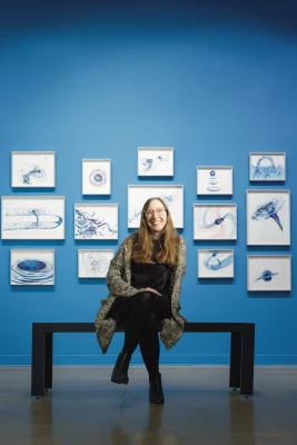 Nancy Stoaks sitting in a gallery surrounded by art.