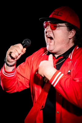 A man in red screaming into a microphone.