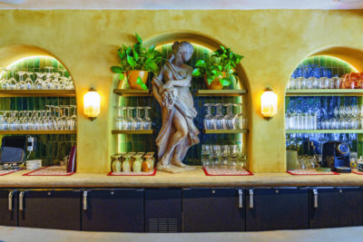 A statue and hanging wine glasses at La Caille's Les Secrets.