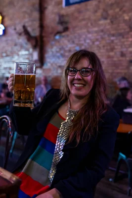 Woman smiles while holding a glass of beer.