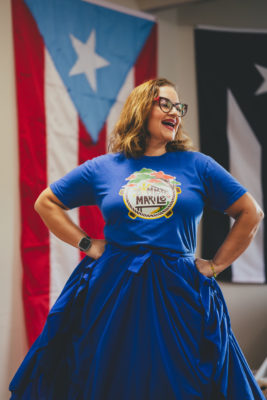 A dancer of Bomba Marilé in front of a Puerto Rican flag.