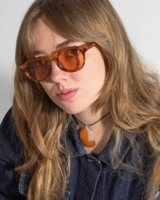 A woman modeling orange-lensed Sidecar glasses