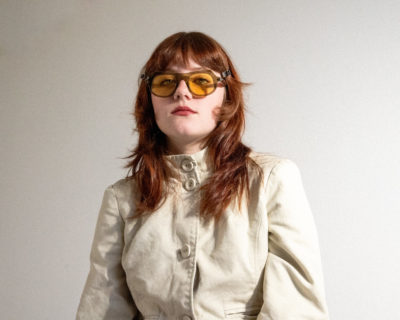 A woman in a white coat modeling Sidecar Glasses.
