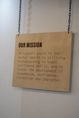 A wooden plaque hanging on the wall at Carry On's Provo indoor skating facility lists the nonprofit's mission.