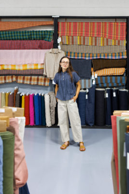 Delaney Dangerfield of Salt Lake Sewciety standing in front of rows of colorful fabric.