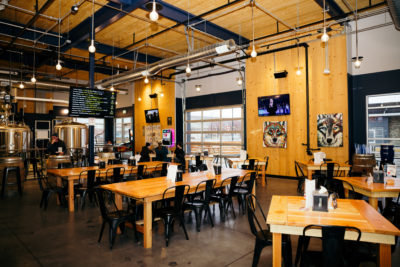 The interior of Wolfdog Brewery--warm golden wood tables, soft lighting, and framed pictures of wolves on the walls.