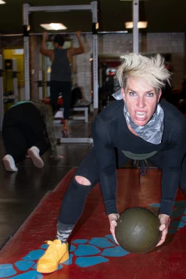 Eliza James squats down with a medicine ball during training, wearing bright yellow sneakers. 