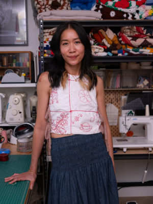 Deedee in a white top and blue dress in her studio.