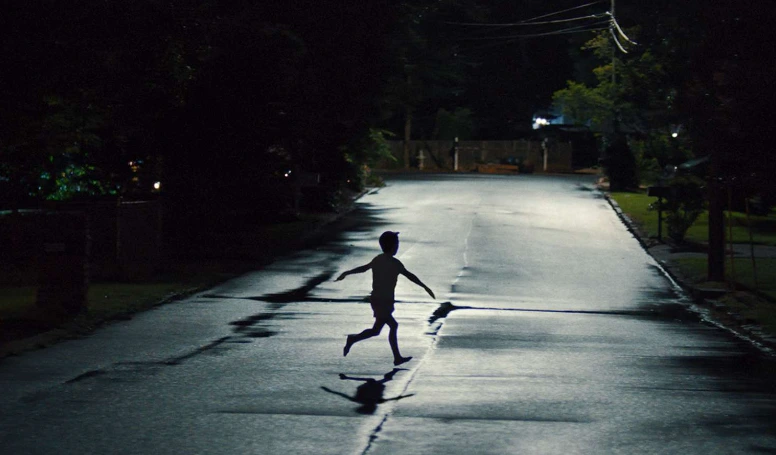 Child running down the street at night.