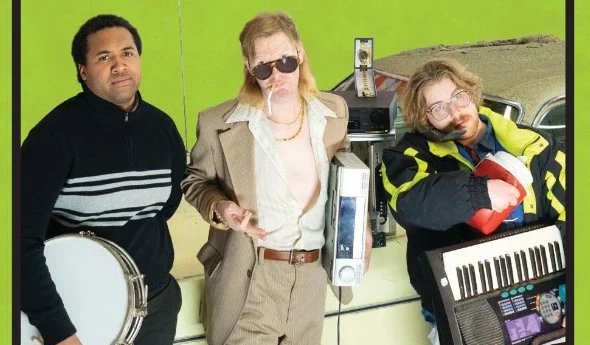 Three guys looking up next to a beat-up car.