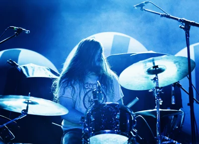 Drummer for Snõõper, Cam Sarret bathed in blue back lighting, on stage at the Union Event Center.