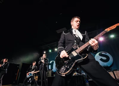 Niklas Almqvist playing guitar with brother Pelle and other Hives band members Mattias and Joey playing while on stage at the Union Event Center, Salt Lake City UT.