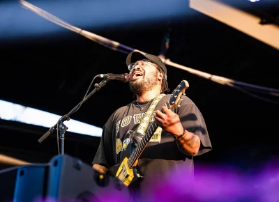 Solo musician Bartees Strange singing at the mic with guitar in hand in Salt Lake City, UT.