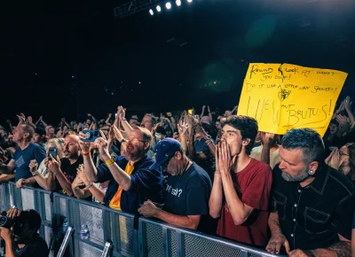 Audience members cheering on during the show while one audience member showing a sign begging for track “B for Brutus” to be played.
