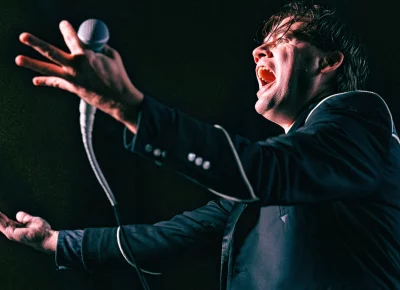 Pelle Almqvist raises his hands with mic in one as he glares at the audience like a madman during the Hives show in Salt Lake City, UT.