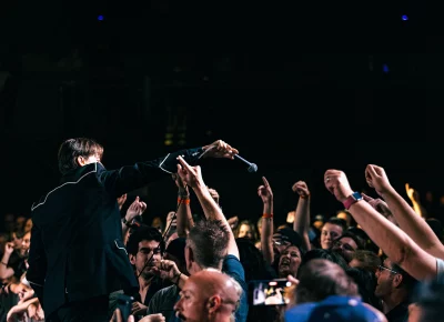Pelle Almqvist of The Hives hops down from the stage and up to the audience as he reaches and hangs the mic over as they sing the lyrics back at him.