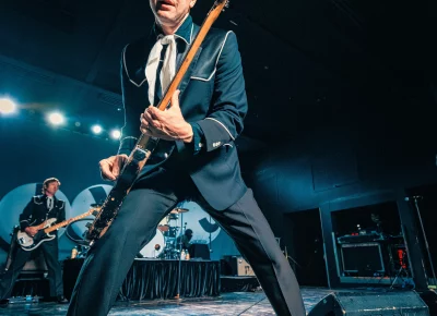 Niklas Almqvist of The Hives stands with legs spread at the edge of the stage during their show at the Union Event Center, Salt Lake City, UT.
