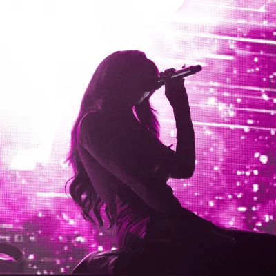 MARINA silhouetted against a sparkly pink screen.