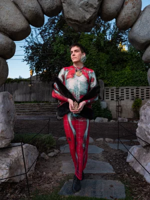 Arthur Diaz standing under a rock arch in a red and blue one-piece.