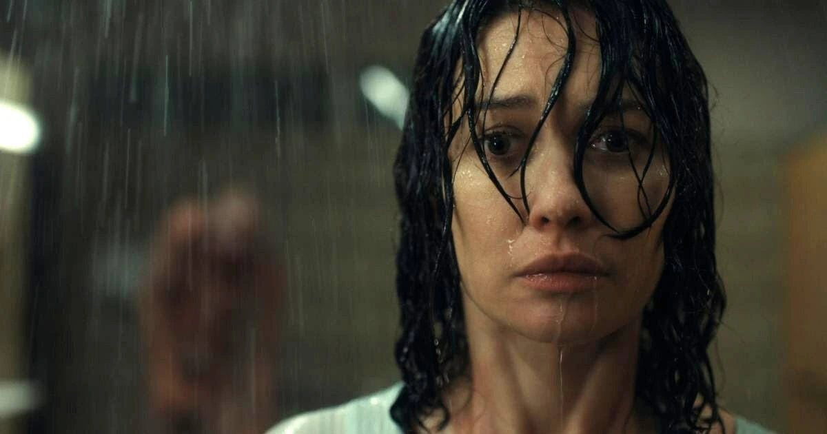 A still of actress Olga Kurylenko as the character Alice standing in the rain, from the 2025 psychological thriller Other.
