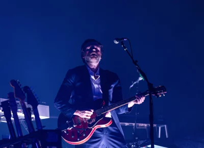 Lord Huron guitarist plays as the set begins and lights feed in from the stage floor below.