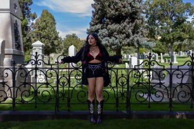 Litzi Estrada standing on a fence in a graveyard.