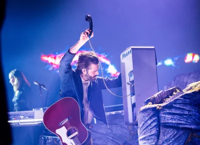 Lord Huron lead vocalist Ben Schneider raising the payphone in hand above his head as the music plays during the Cosmic Selector tour at the UCCU Center in Orem, UT.