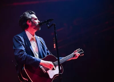 Ben Schneider of Lord Huron playing guitar and singing at the mic, on stage at the UCCU Center in Orem, UT.