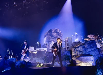 Lord Huron plays on stage, with Ben Schneider (center) holding the payphone to his mouth and looking at the audience while singing into the mic during the show at the UCCU Center in Orem, UT.
