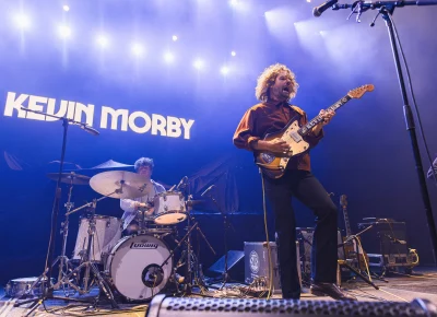 Kevin Morby on stage with his tour drummer (left) and bassist just sneaking in (right), photographed in Orem, UT at the UCCU Center.