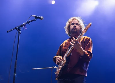 Kevin Morby stares down the barrel of the lens, on stage while playing an opening set for Lord Huron.