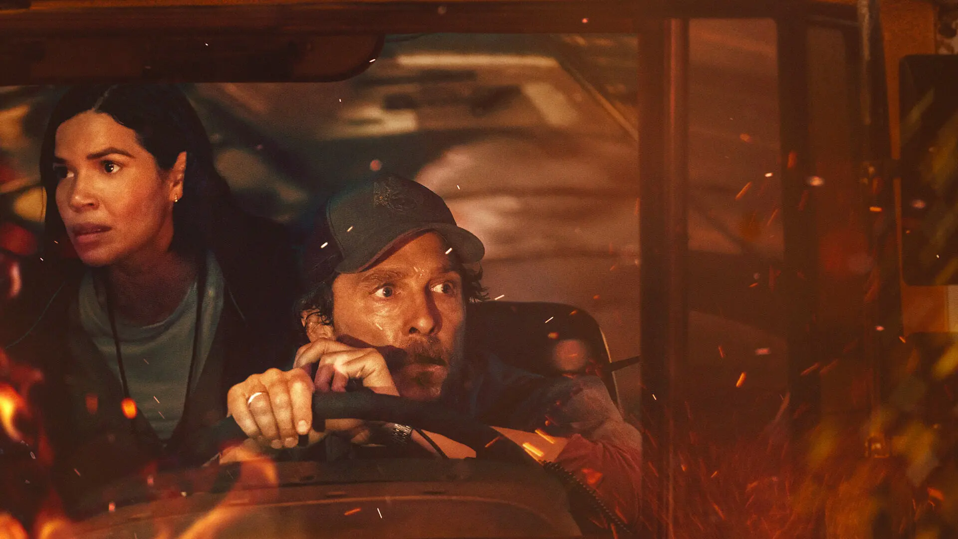 America Ferrera and Matthew McConaughey look frightened in a car surrounded by flames.