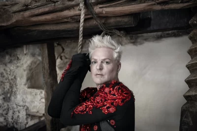 Andy Bell in a sequin body suit holding onto a rope.